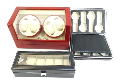 A group of watch cases, to include a red lacquered case with Perspex front enclosing two cylindrical stands, to hold two watches each, 33cm wide, and two further cases.