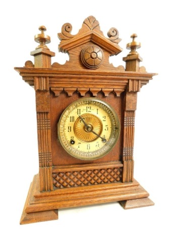 An early 20thC oak cased American mantel clock, the brass circular dial with brass chapter ring bearing Arabic numerals, with Ansonia Clock Co New York USA movement, the case with carved top section and turned finials, 39cm high, with key and pendulum.