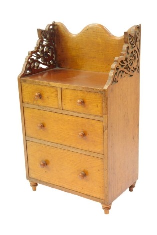 A 19thC oak apprentice's chest, the top with a raised back with carved sides, above two short and two graduated long drawers, on turned feet, 43cm high, 25cm wide, 16cm deep.