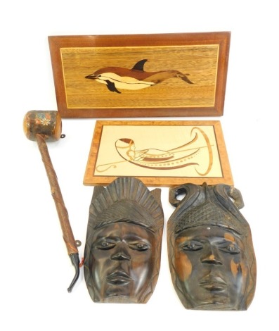 A group of treen, to include two carved masks, two inlaid wooden wall plaques depicting a dolphin, and an ecclesiastical type figure, together with a pipe with transfer printed floral decoration, 31cm long.