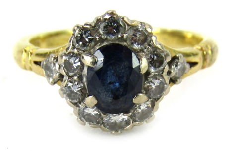 An 18ct gold sapphire and diamond dress ring, the oval cut sapphire in four claw setting, 5.6mm x 4.4mm x 2.2mm, surrounded by tiny diamonds, on V splayed shoulders, with import marks, London 1996, ring size J, 3.4g all in.