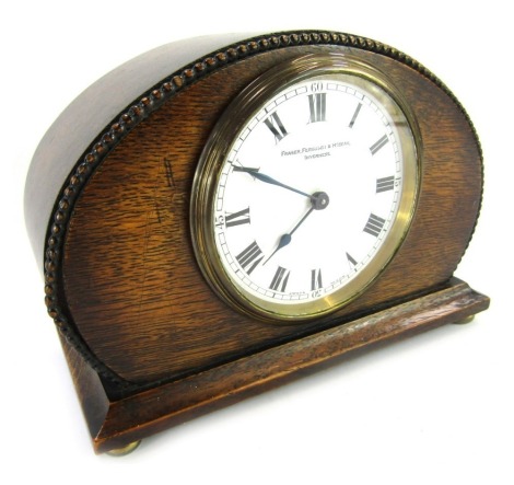 An early 20thC oak cased mantel clock, the circular white enamel dial bearing Roman numerals for Fraser, Ferguson and McBean Inverness, the movement for Buren numbered 103067, the case of oval compressed form with carved bead border, on stepped base on fo