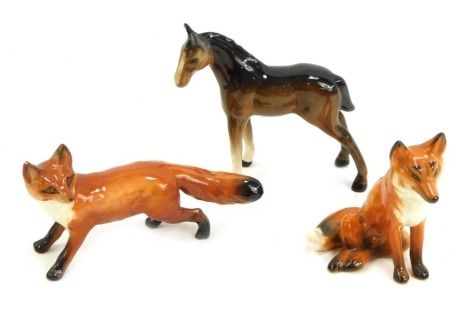 Three Beswick pottery figures, comprising seated fox, standing fox, and brown foal, the foal 9cm high.