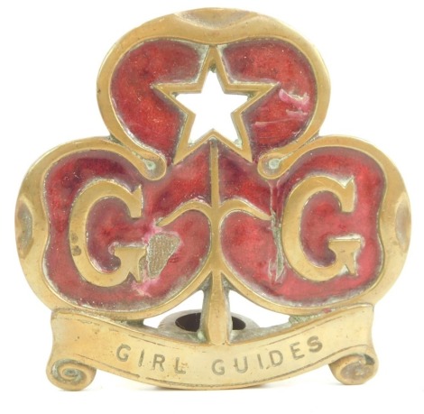 A brass and enamelled Girl Guides emblem, c1910, Regd No 671782, 11cm wide. (AF)