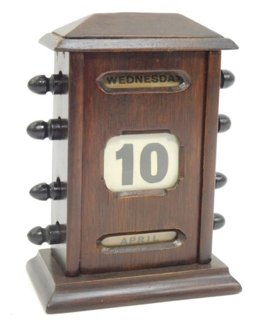 An early 20thC oak perpetual desk calendar, with ebonised turners, displaying day, date and month, on a stepped rectangular base, 19cm high, 13cm wide, 7cm deep.