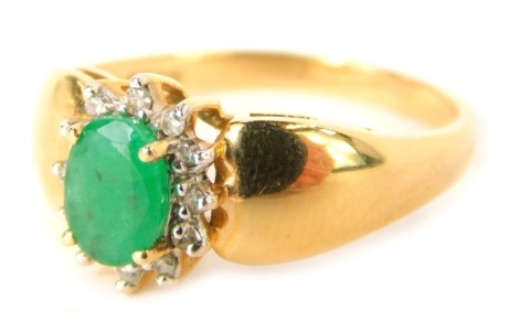 An emerald and diamond floral cluster ring, the oval emerald in a four claw setting, 6.8mm x 4.8mm x 2.2mm, surrounded by tiny diamonds, on a yellow metal band stamped 750, size Q, 3.3g all in.