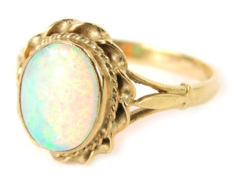 A 9ct gold opal dress ring, the oval opal in a rub over setting with twist outer border, on V splayed shoulders, Birmingham 1984, ring size P½, 3.4g all in.