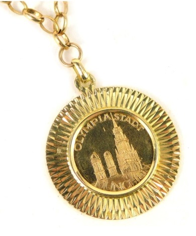 An Olympiastadt Munchen 1972 commemorative coin, in a gold plated frame, on a curb link neck chain, yellow metal stamped 375, 54cm long, the chain 10g.