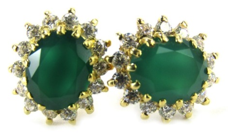 A pair of emerald and diamond cluster earrings, the oval emerald in a claw setting, surrounded by tiny diamonds, the yellow metal frame unmarked, with single pin backs and butterfly backs, 4.6g all in.