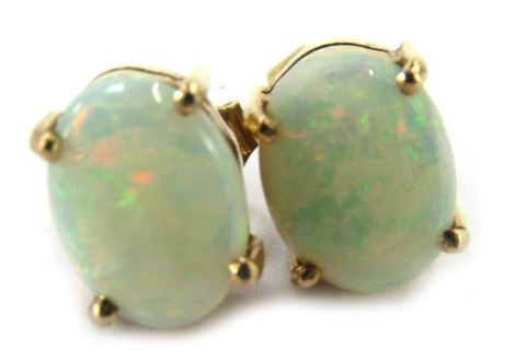 A pair of opal stud earrings, each set with an oval opal in four claw basket setting, on a yellow metal stem stamped 375, 1.1g all in.