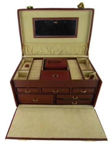 A brown leatherette jewellery box, of three tiered design with brass hinged top, opening to reveal a cream lined top above an arrangement of drawers, 17cm high, 32.5cm wide, 21cm deep. (carry strap AF)