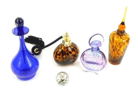 A group of coloured glass ware, comprising a Swarovski crystal paperweight, an Alex Jackson 267B purple decanter and stopper, a blue Bristol glass decanter and stopper, a leopard print design glass perfume bottle and associated decanter and stopper. (5)