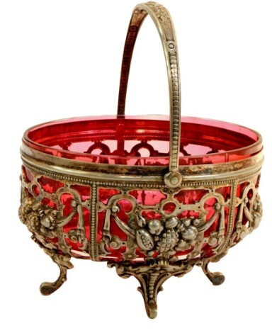 A Victorian silver plated and cranberry glass sweet meat dish, the pierced basket with a swing handle and cranberry glass interior bowl, 10cm high, 15cm wide.