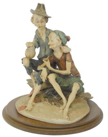 A Capodimonte figure group, of two figures smoking a pipe and drinking, unmarked, on a circular mahogany base, 50cm high, 40cm wide.