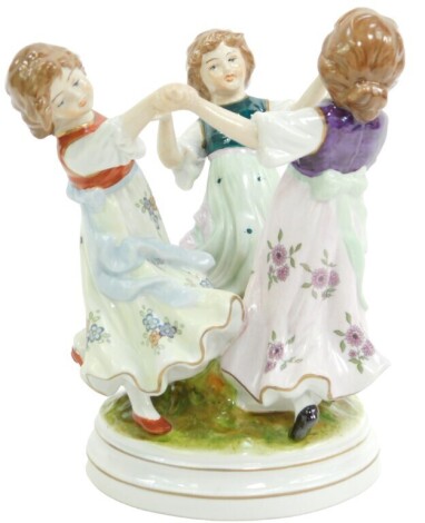 A 20thC Continental porcelain figure group, of three girls dancing, on a circular base, blue printed mark, 17cm high.