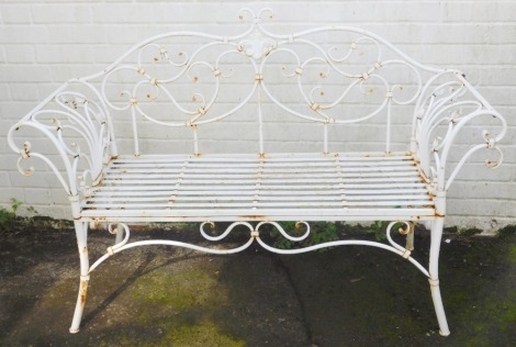 A 20thC wrought metal two seater garden bench, in white, with scroll motifs and slatted base, 142cm wide.