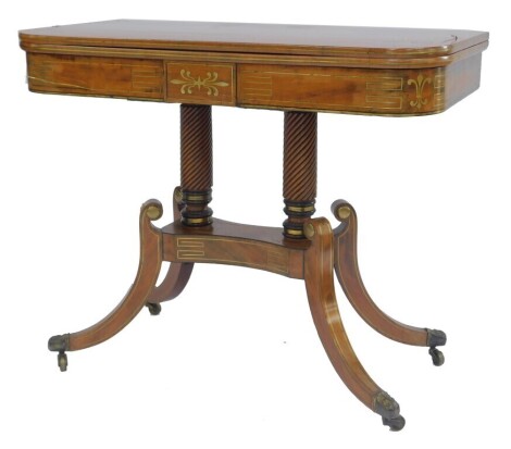 A Regency mahogany and brass inlaid tea table, the rounded top with scrolling brass inlay, on two spiral turned columns, with a shaped base, undertier on sabre legs with brass leaf capped castors, 74cm high, 92cm wide, 45cm deep. (AF)