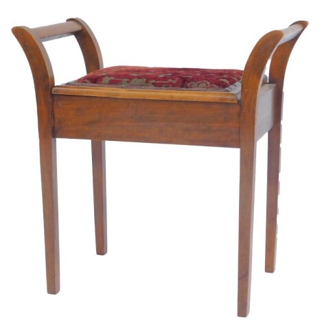 An Edwardian mahogany piano stool, with outswept arms, overstuffed seat, the hinged section on square legs.