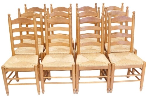 A set of twelve oak ladder back dining chairs, each with a rush seat, on turned legs with stretchers.