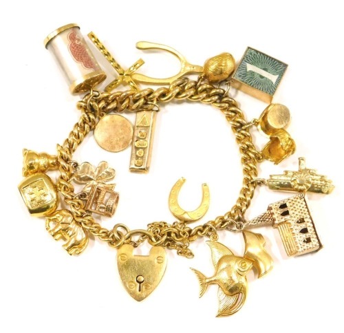 A 9ct gold charm bracelet, the curb link bracelet with safety chain and heart shaped padlock, various 9ct gold charms to include elephant, wishing well, clover, bell, ten shilling money roll, miniature gold ingot, wish bone, cross, shell hat, crib, boat,