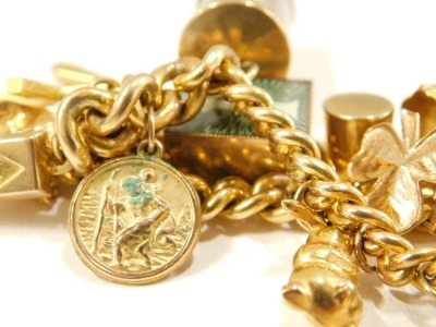 A 9ct gold charm bracelet, the curb link bracelet with safety chain and heart shaped padlock, various 9ct gold charms to include elephant, wishing well, clover, bell, ten shilling money roll, miniature gold ingot, wish bone, cross, shell hat, crib, boat, - 4