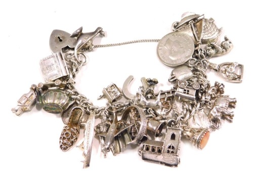 A silver charm bracelet, the curb link bracelet, with safety chain in heart shaped padlock, and various charms, to include elephant, shilling, church, horse, horse shoe, St Christopher pendant, boat, kettle, aeroplane, and others, some marked 925, others