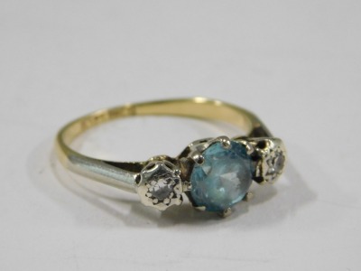 A blue zircon and diamond three stone dress ring, the central zircon in a six claw setting, flanked by two tiny diamonds, each in illusion platinum setting, on a yellow metal band stamped 18ct plat, ring size M, 2.8g all in, boxed. - 2