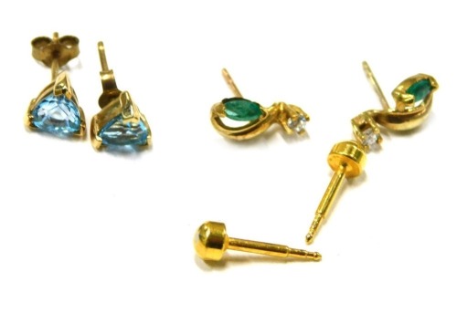 Three pairs of earrings, comprising a pair of 9ct gold and blue zircon triangular cut stud earrings, a pair of yellow metal emerald and diamond set drop earrings, 1cm high, unmarked, and a pair of starter studs, 2.5g all in. (3)