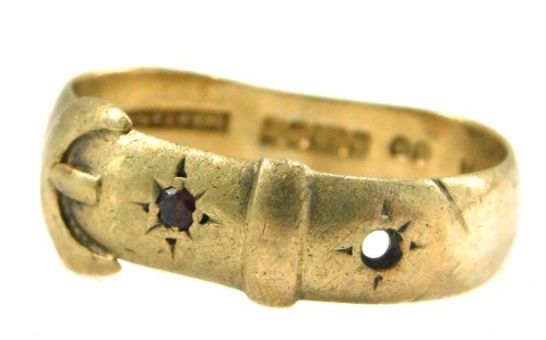 A 9ct gold buckle ring, set with one garnet and one vacant stone, maker JH, Birmingham 1909, misshapen, 4.8g all in.