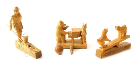 Three carved wooden animal figure groups, comprising goats on saw, man fishing, and bear playing piano, the largest 18cm wide.