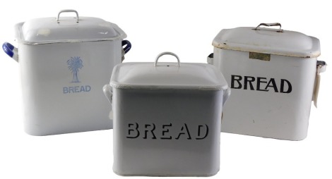 Three enamel bread bids, comprising a cream enamel bread bin and lid, 29cm high, a cream and blue enamel bread bin, 30cm high, with lid, and a white and black enamel bread bin with lid, 28cm high. (3)