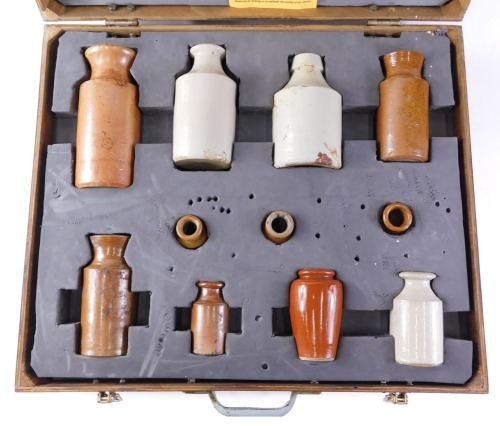 A collection of 19thC and later stoneware bottles, each brown or cream treacle glazed, in fitted ply case, the largest 17cm high.