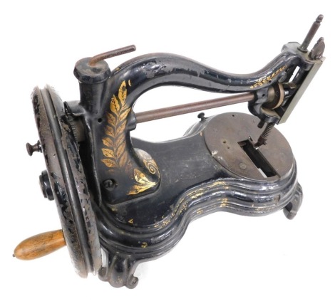 A 19thC sewing machine, on black cast base, with gilt leaf decoration and spun handle, on splayed legs, 29cm high, in plywood travel case.