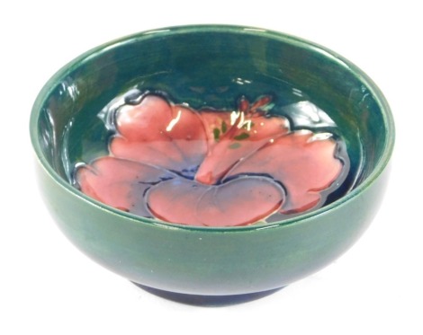 A Moorcroft anenome pattern pin dish, on green glazed ground bearing label, 8cm diameter.