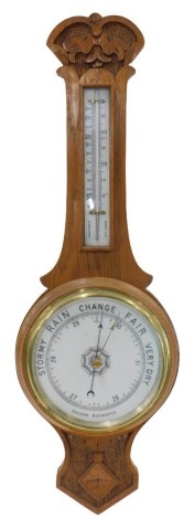 A 19thC oak aneroid barometer, with white painted dial, carved top, 76cm high.