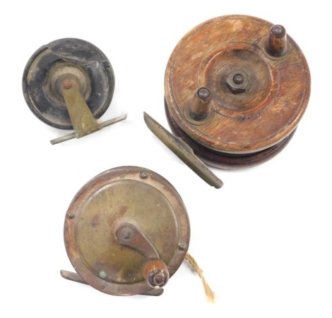 Three fishing reels, comprising a Nottingham style wooden reel, 7cm diameter, and two other reels, 6cm and 4cm diameter. (3)