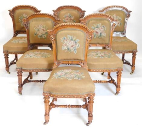 A set of fourteen Victorian elm and burr elm dining chairs, each with an arched gadrooned back with moulded leaf carved supports, with a wool work padded back and seat, on turned tapering fluted legs, with H stretcher and ceramic castors.