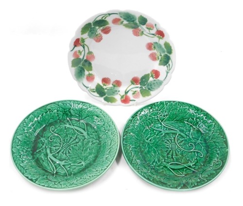 A French Luneville plate decorated with a band of strawberries, and two Wedgwood green leaf moulded plates. (3)