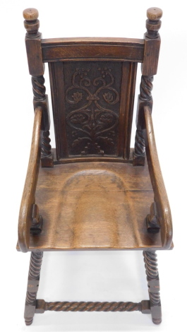 A carved oak child's highchair in 18thC style, with a carved back, shaped arms and solid seat, on spirally turned legs.