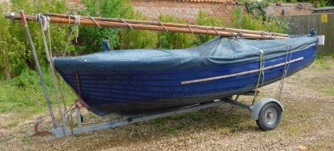 A 12ft blue G.R.P Clinker Sailing Dingy, with a mahogany gunwale with brass fittings, with Neil Pryde Tri-Radial 4 sail, mast and rigging, buoyancy bags, paddles, with boat top cover in blue, on its own steel road trailer. 