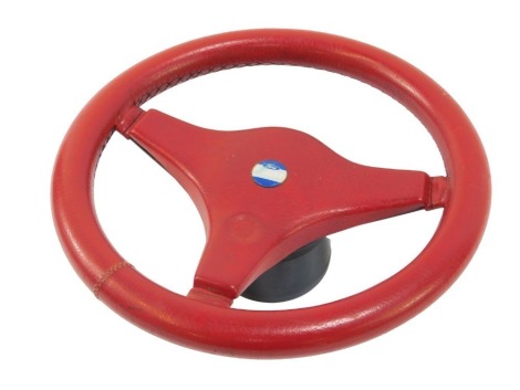 A Ford Escort red leather steering wheel, with applied blue crest, 34cm diameter.