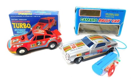 A Daishin battery operated Porsche Turbo stock racer, with pump and go action, boxed, and a Asahi battery operated remote control heavy duty metal Camaro rally car, boxed. (2)