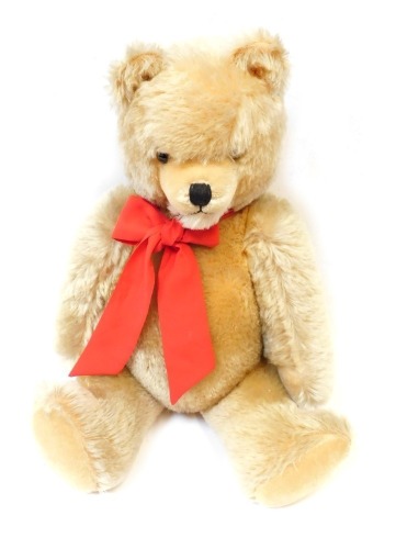 A 19thC plush blonde jointed teddy bear, with wire wool filling and pad paws, with red bow, 51cm high.