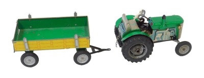 A modern tinplate clockwork tractor and trailer set, with key, painted in green with yellow trailer.