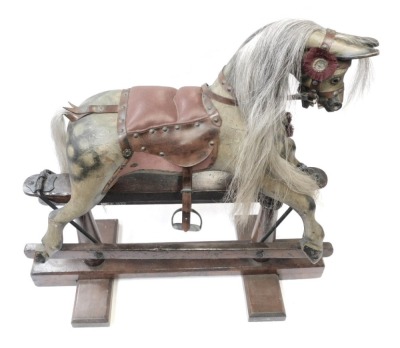 A 20thC rocking horse, the dapple grey horse with bound saddle, on a trestle base, 89cm high, 75cm wide, 38cm deep.