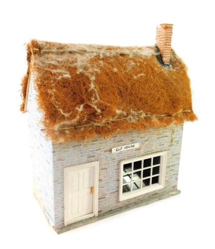 A wooden kit built doll's house, with a thatched roof, with applied brick detail, and various Christmas figures entitled Elf House, 49cm high, 38cm wide, 20cm deep. (AF)