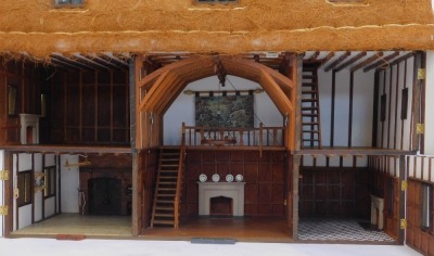 A three storey substantial Tudor style doll's house, with three chimneys, thatched roof, in painted Gothic style with panelled windows and doors and partially fitted interior, 103cm high, 120cm wide, 53cm deep. (AF) - 3