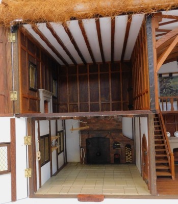 A three storey substantial Tudor style doll's house, with three chimneys, thatched roof, in painted Gothic style with panelled windows and doors and partially fitted interior, 103cm high, 120cm wide, 53cm deep. (AF) - 6