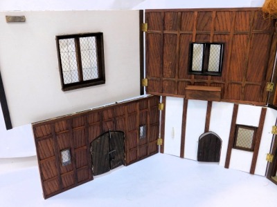 A three storey substantial Tudor style doll's house, with three chimneys, thatched roof, in painted Gothic style with panelled windows and doors and partially fitted interior, 103cm high, 120cm wide, 53cm deep. (AF) - 8