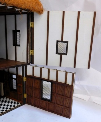 A three storey substantial Tudor style doll's house, with three chimneys, thatched roof, in painted Gothic style with panelled windows and doors and partially fitted interior, 103cm high, 120cm wide, 53cm deep. (AF) - 9